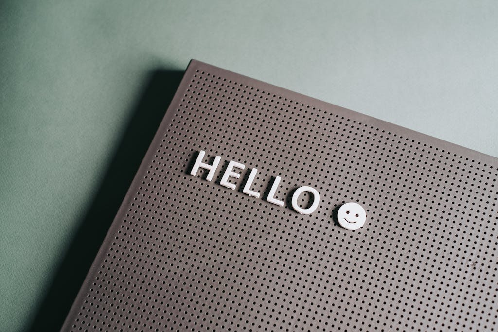 Close-up of a minimalist letter board with 'Hello' text and smiley face on a green backdrop.