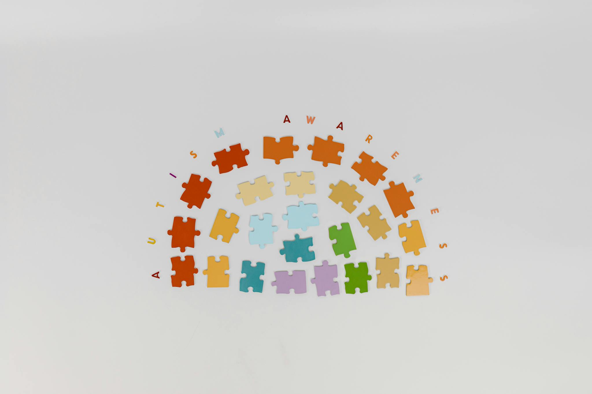 Colorful puzzle pieces arranged to promote autism awareness on a light background.